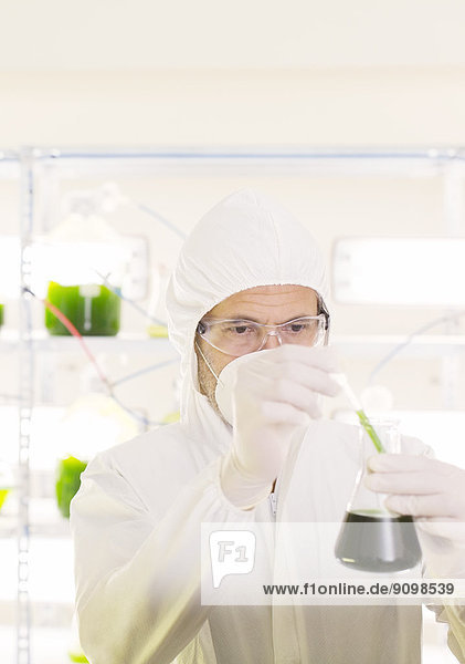 Wissenschaftler im sauberen Anzug mit Becherglas im Labor