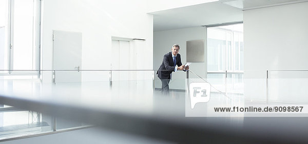 Businessman standing at railing in office