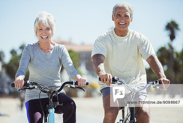 Portrait of senior couple riding bicycles on beach