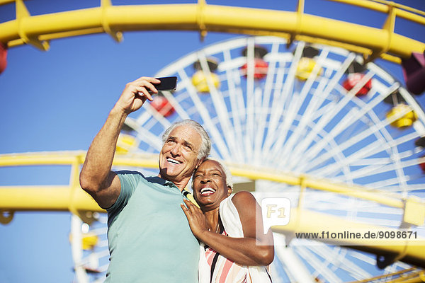Seniorenpaar nimmt Selfie im Vergnügungspark mit.