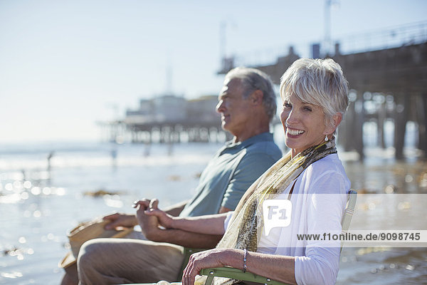 Porträt eines Seniorenpaares in Liegestühlen am Strand