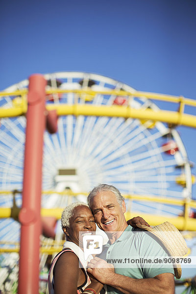 Porträt eines glücklichen Seniorenpaares beim Umarmen im Vergnügungspark