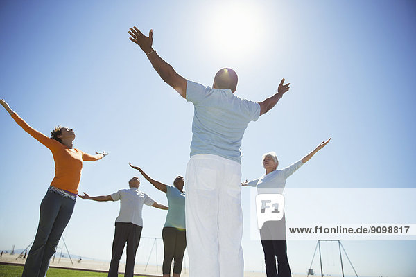 Senioren beim Yoga unter sonnigem  blauem Himmel