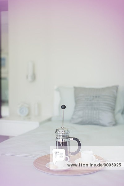 Französischer Presskaffee und Tassen auf Tablett im Schlafzimmer