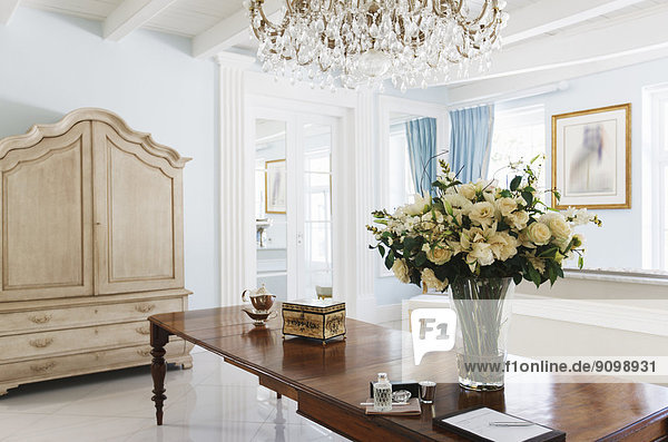 Kronleuchter über Rosenstrauß auf Tisch im luxuriösen Foyer