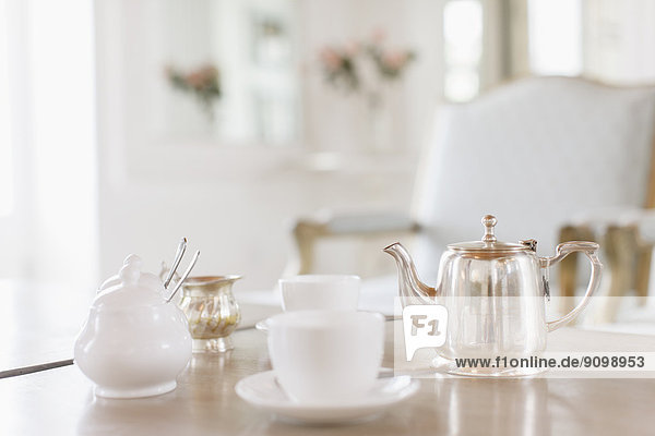 Teacups and silver teapot on table