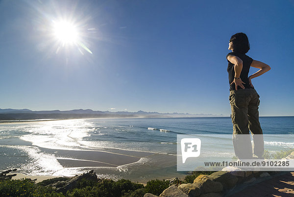 Young woman looking at a bay and the Indian Ocean  Plettenberg Bay or Plettenbergbaai  Garden Route  Eden District  Western Cape  South Africa