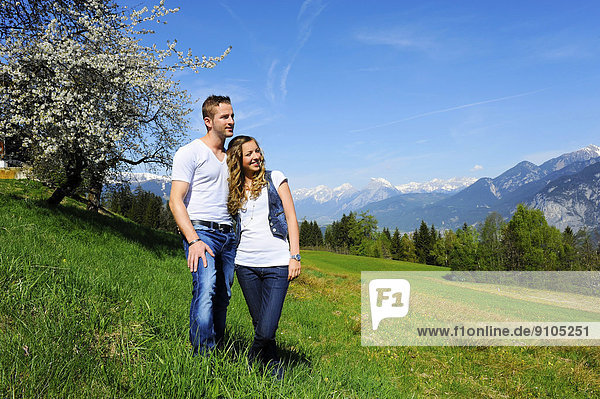 Liebespaar im Frühling  hinten ein blühender Baum und Berge  Götzens  Tirol  Österreich
