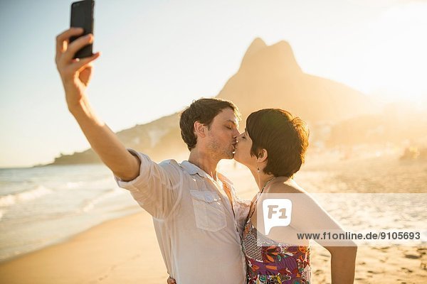 Young couple photographing themselves kissing  Ipanema Beach  Rio  Brazil