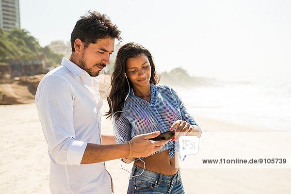 Couple choosing music from smartphone  Arpoador beach  Rio De Janeiro  Brazil