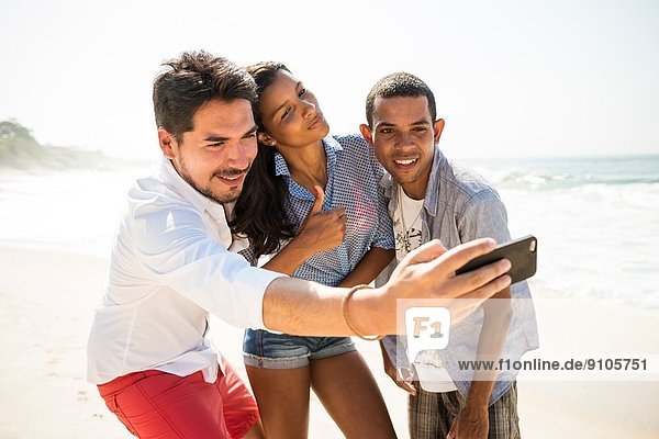 Friends taking self portrait on smartphone  Arpoador beach  Rio De Janeiro  Brazil