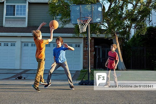 Jungs spielen Basketball vor dem Haus