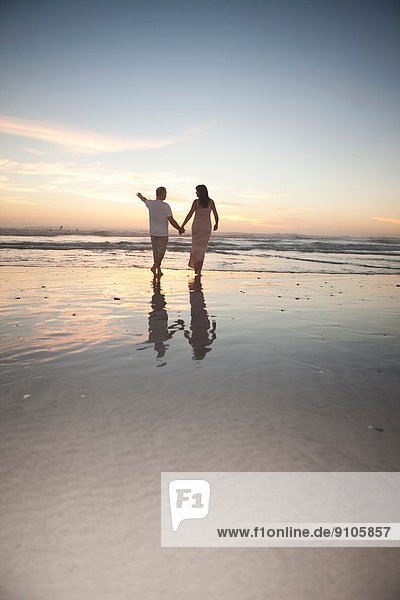 Couple holding hands on beach at sunset  Cape Town  South Africa
