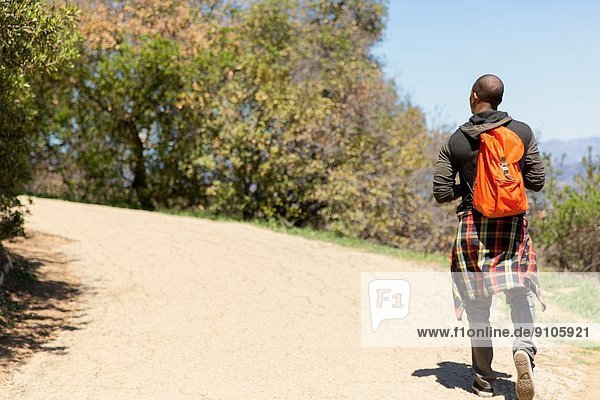 Junger Mann mit Rucksack beim Spaziergang im Park