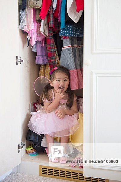 Girl in princess costume hiding in cupboard