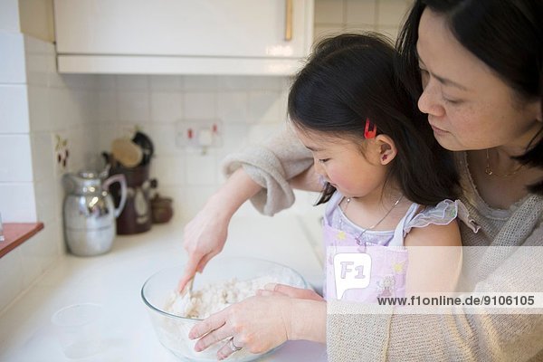 Mutter und Tochter in der Küche  Zutaten in Schüssel mischen