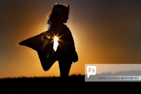 Silhouette des jungen Mädchens in geflügeltem Feenkostüm bei Sonnenuntergang