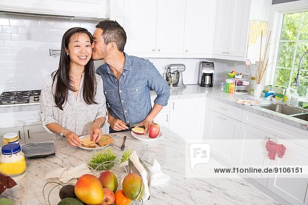 Romantisches mittleres erwachsenes Paar bei der Zubereitung eines Sandwiches an der Küchentheke