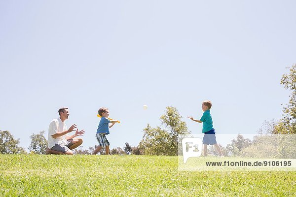 Vater und Söhne spielen Baseball im Park