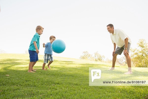Vater und Söhne beim Ballspielen im Park