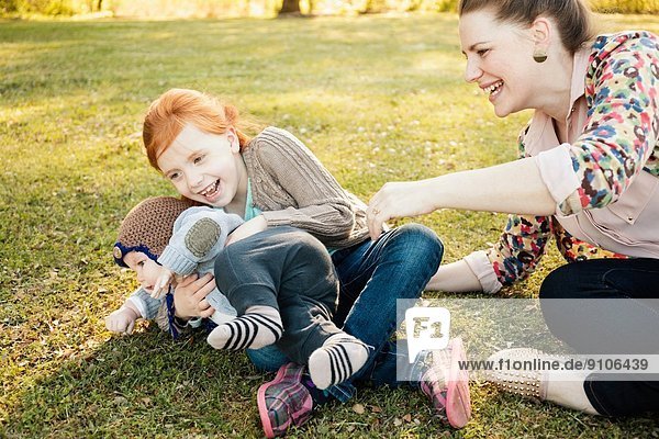 Mittlere erwachsene Mutter Tochter und kleiner Sohn auf Rasen im Park