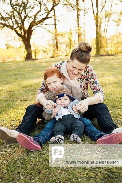 Portrait of mid adult mother daughter and baby son in park