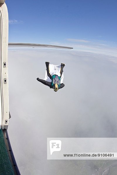 Mittlerer Erwachsener Mann  der im Wingsuit über Wolken fliegt.