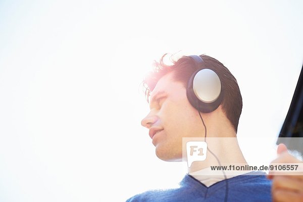 Junger Mann mit Kopfhörer beim Musikhören