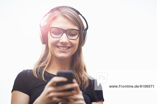 Junge Frau mit Kopfhörer über Smartphone