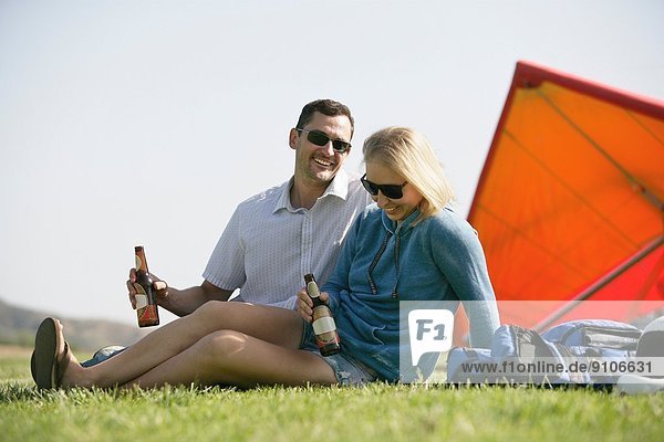 Paar beim Bier entspannen  Drachenflieger im Hintergrund