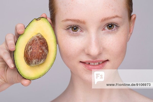 Porträt einer jungen Frau  die Avocado hält