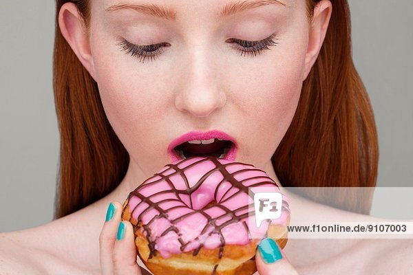 Junge Frau beißt Donut