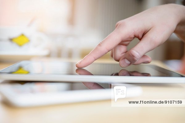 Nahaufnahme der Hand der jungen Frau mittels Touchscreen auf digitalem Tablett