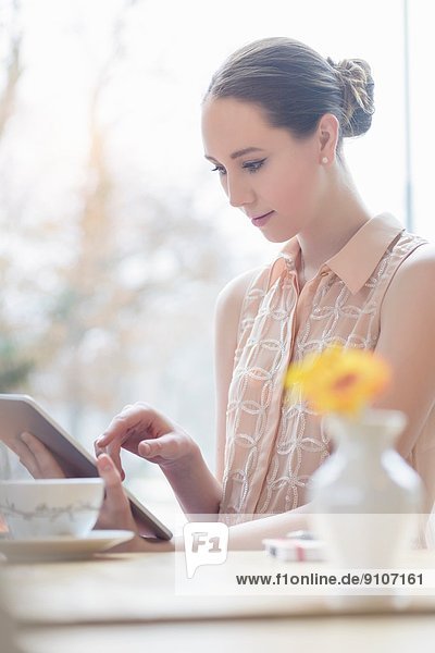 Junge Geschäftsfrau im Café mit digitalem Tablett