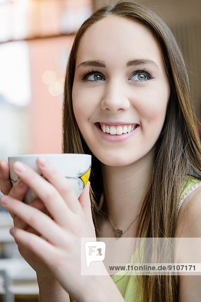 Nahaufnahme Porträt einer jungen Frau beim Kaffeetrinken im Cafe