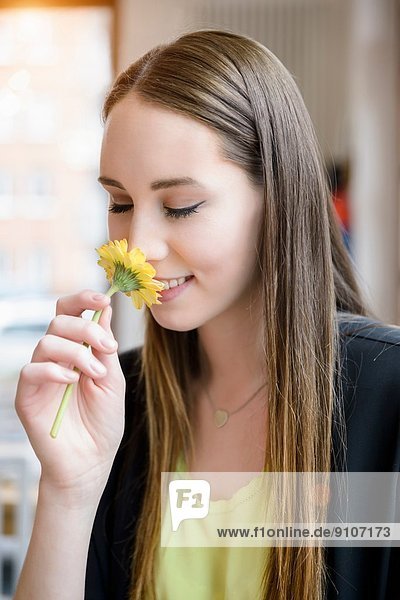 Porträt einer jungen Frau in einem Café mit duftender Blume