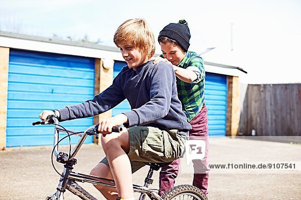 Boy giving friend a ride on back of bike