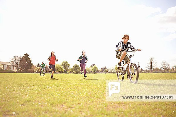 Gruppe von Jungen beim Laufen und Radfahren auf dem Spielfeld