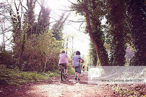 Boy on bike with friend on forest path