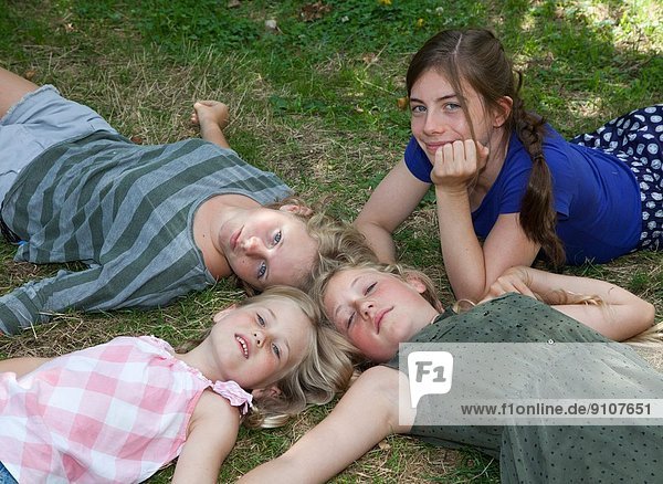 Vier Mädchen auf Gras liegend