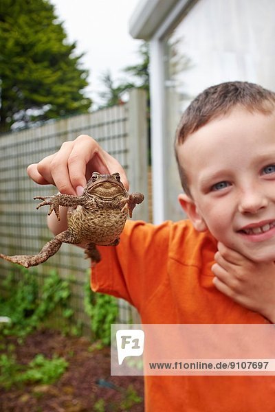Porträt eines Jungen im Garten mit Krötenhaltung