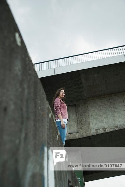 Young woman standing on wall  low angle