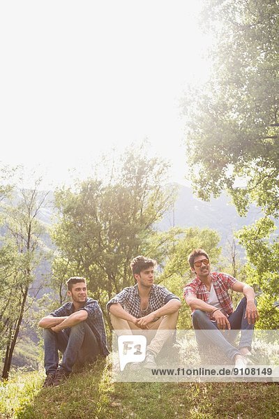 Three young men sitting on grass