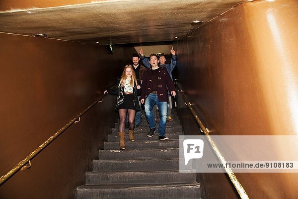 Gruppe von Freunden  die die Treppe hinunter in den Nachtclub kommen.