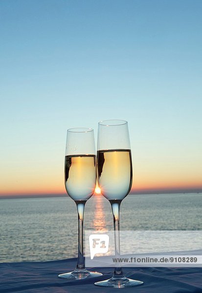 Zwei Champagnerflöten gegen Sonnenuntergang