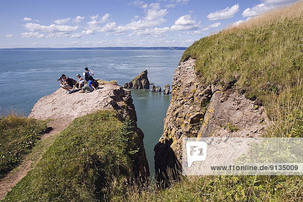Hikers view the rock formations from atop cliffs at the end of the Cape Split hiking trail along Nova Scotia's Bay of Fundy coast.