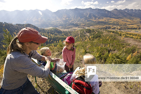 Woman with daughters relax on bench during hiking on Castle Mountain Trail in autumn  Fernie  BC  Canada.