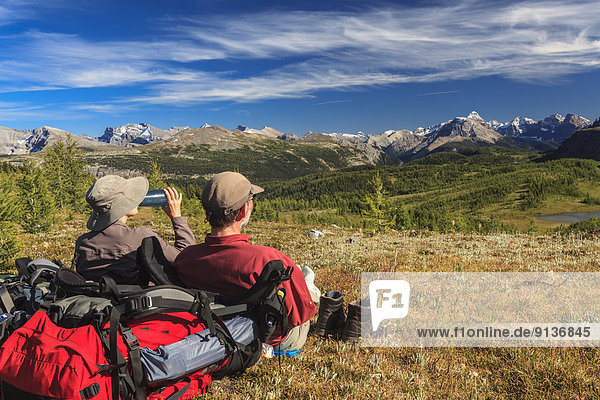Two hikers rest while enjoying the view of the Monarch and Ramparts from Healy Pass  Banff National Park  Alberta Canada.Model Released