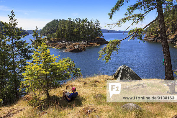 A kayaker relaxes on Penn Island in Sutil Channel between Read and Cortes Islands British Columbia Canada. Model Released