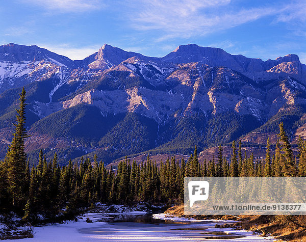A winter scenic of the magestic rocky mountains of Jasper National Park of western Alberta Canada with a small half frozen pond nestled in the forground.